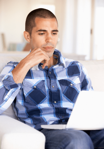 Man in plaid shirt looking at his laptop.